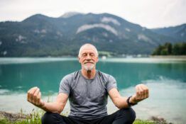 a senior man pensioner sitting by lake in nature d YU5WXKZ scaled